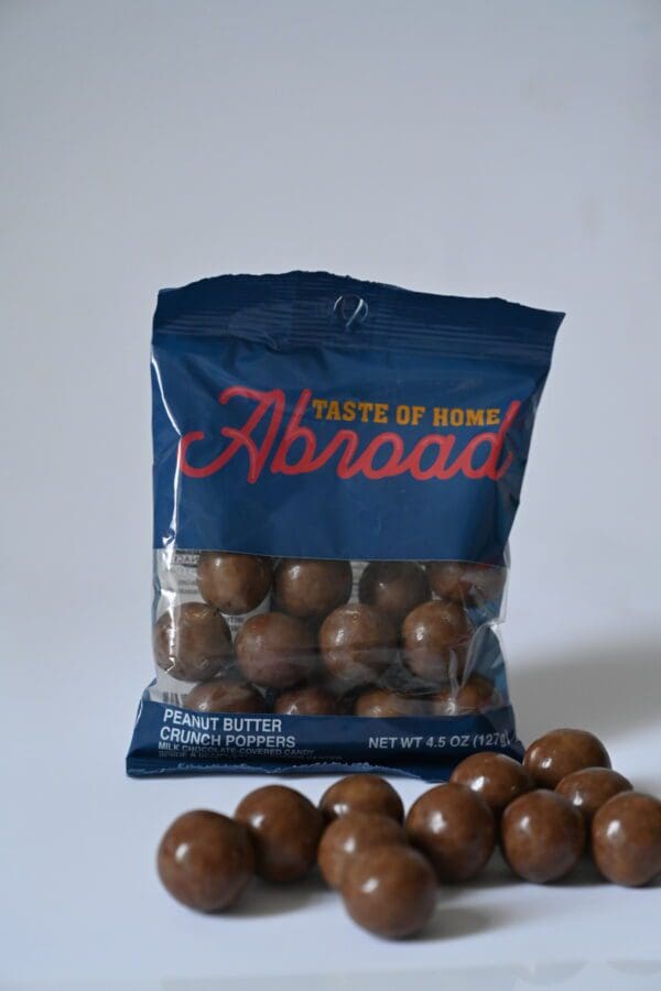 A bag of peanut butter covered peanuts sitting next to other nuts.