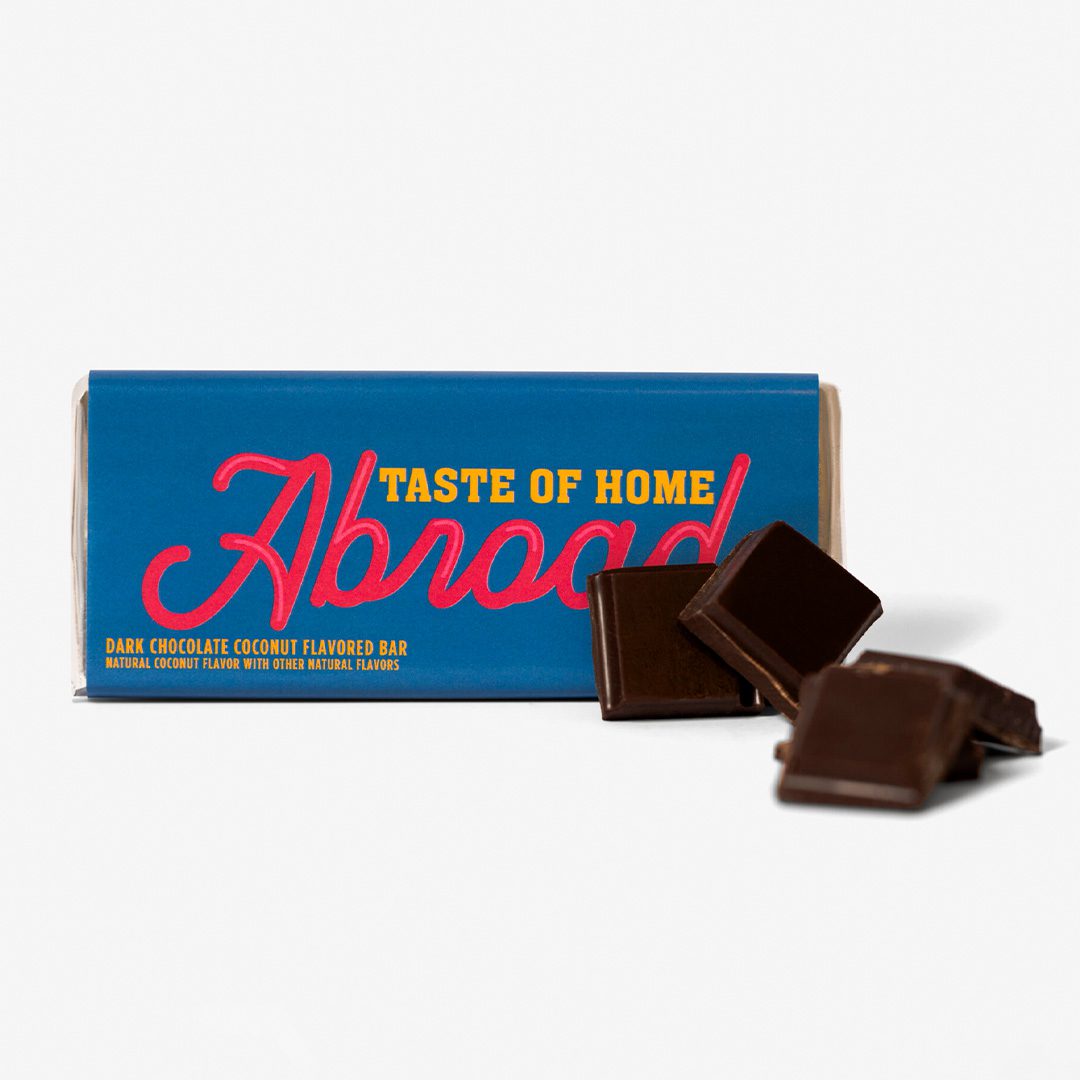 A dark chocolate coconut flavored bar with its packaging and a few pieces broken off in front.