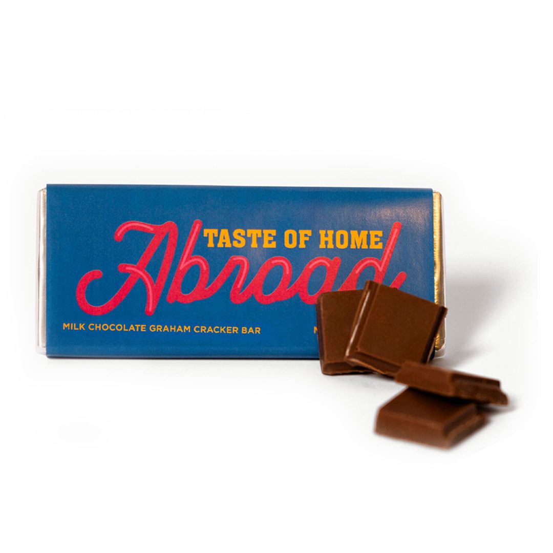 Box of "abroad" milk chocolate graham cracker bar with pieces of chocolate beside it.