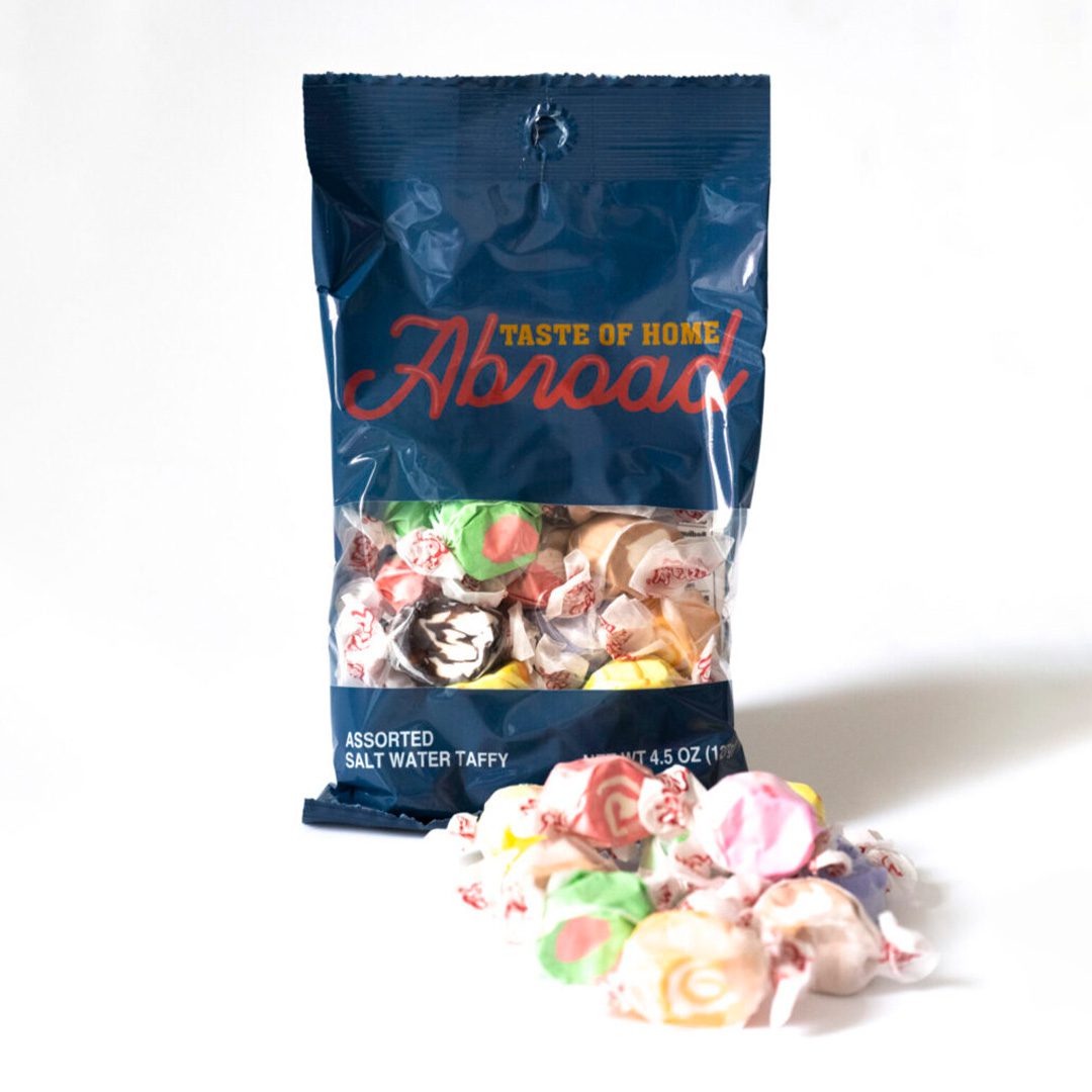 A bag of "taste of home abroad" assorted saltwater taffy with some candies outside the package.