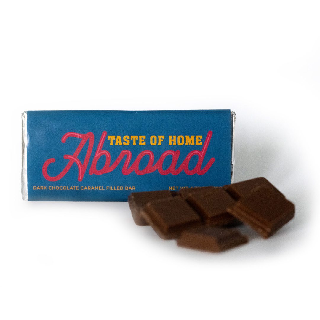 A dark chocolate caramel filled bar with its packaging labeled "taste of home abroad.