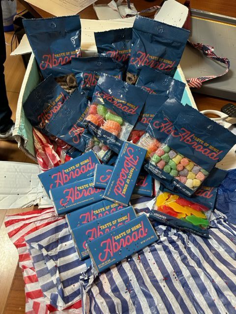 An opened package with various snack bags and colorful wrappers scattered on top of a striped packing material.